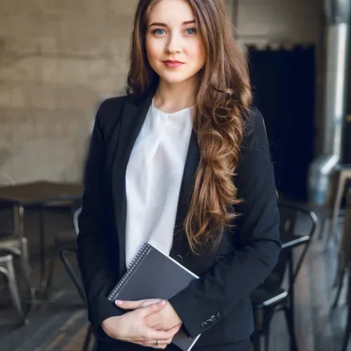 1c14010479af25886799bd0fd0d8a19b.brunette-business-woman-with-wavy-long-hair-blue-eyes-stands-holding-notebook-hands-768x1152-1-qmuk52z0142euw7g77gyvmp2olely55yjhtrdwjs08